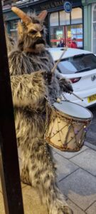 A person wearing traditional Krampus outfit for the Krampus Run banging a drum