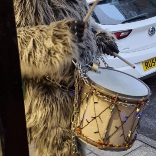 35cfd1d1-97df-467b-a4a3-9114d32b0d35 A person wearing traditional Krampus outfit for the Krampus Run banging a drum