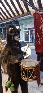 A person wearing traditional Krampus outfit for the Krampus Run banging a drum